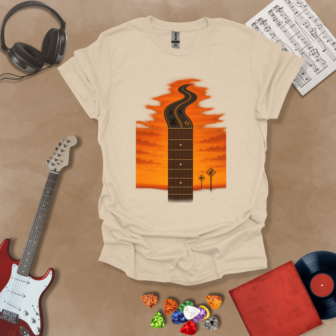 Beige t-shirt with long guitar neck blending into a road under sunset sky.