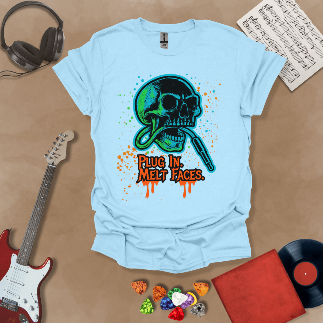 Light blue t-shirt with neon-colored skull biting a guitar cable, paint splatter effect, text “Plug In. Melt Faces.”