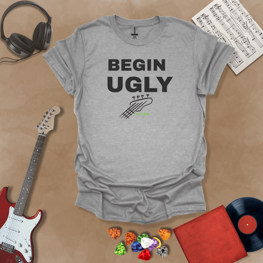Begin Ugly – Jax Edition gray graphic t-shirt featuring bold stacked text with distressed guitar headstock accent and subtle Riff Junkie branding. Motivational creator apparel design.
