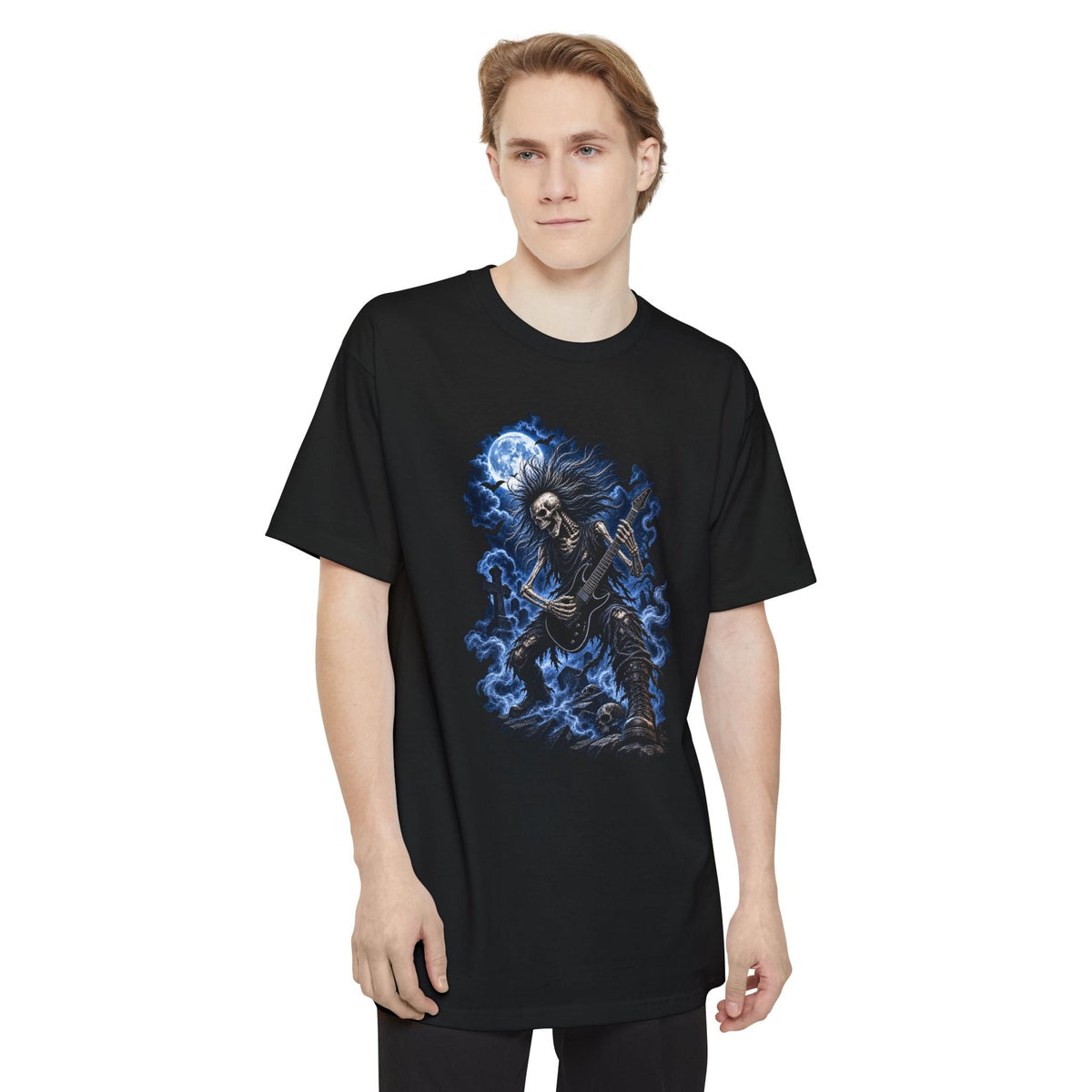 A man wearing a black short-sleeve crewneck t-shirt featuring a graphic print of Grave Shredder Halloween graphic featuring an undead skeleton guitarist rising from the grave while playing an electric guitar.