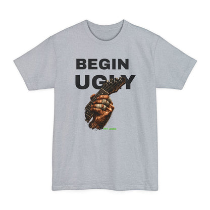 A gray short-sleeve t-shirt featuring a graphic print on the front. The design displays the text 'BEGIN UGLY' in a distressed cream-colored font above an illustration of a hand holding a guitar, with  "Riff Junkie" in neon green.