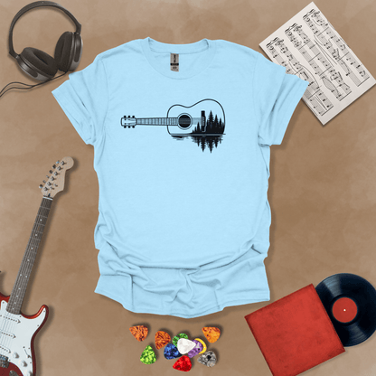 Light blue t-shirt with a black graphic of an acoustic guitar, featuring a reflection of pine trees and water inside the guitar body.