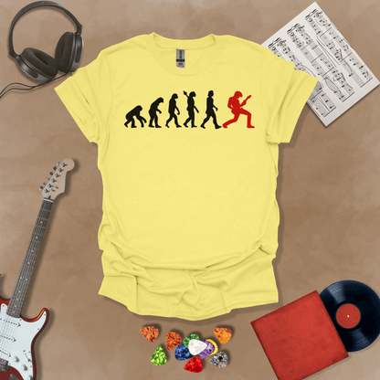 Yellow t-shirt with a black and red evolution graphic, showing the progression from ape to modern human, ending with a red silhouette of a guitarist rocking out.