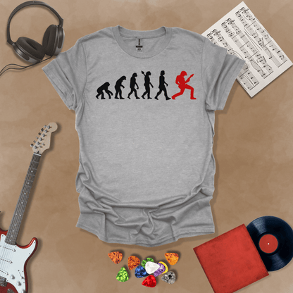 Gray t-shirt with a black and red evolution graphic, showing the progression from ape to modern human, ending with a red silhouette of a guitarist rocking out.