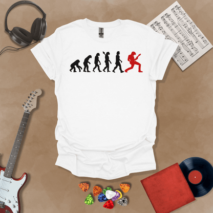 White t-shirt with a black and red evolution graphic, showing the progression from ape to modern human, ending with a red silhouette of a guitarist rocking out.