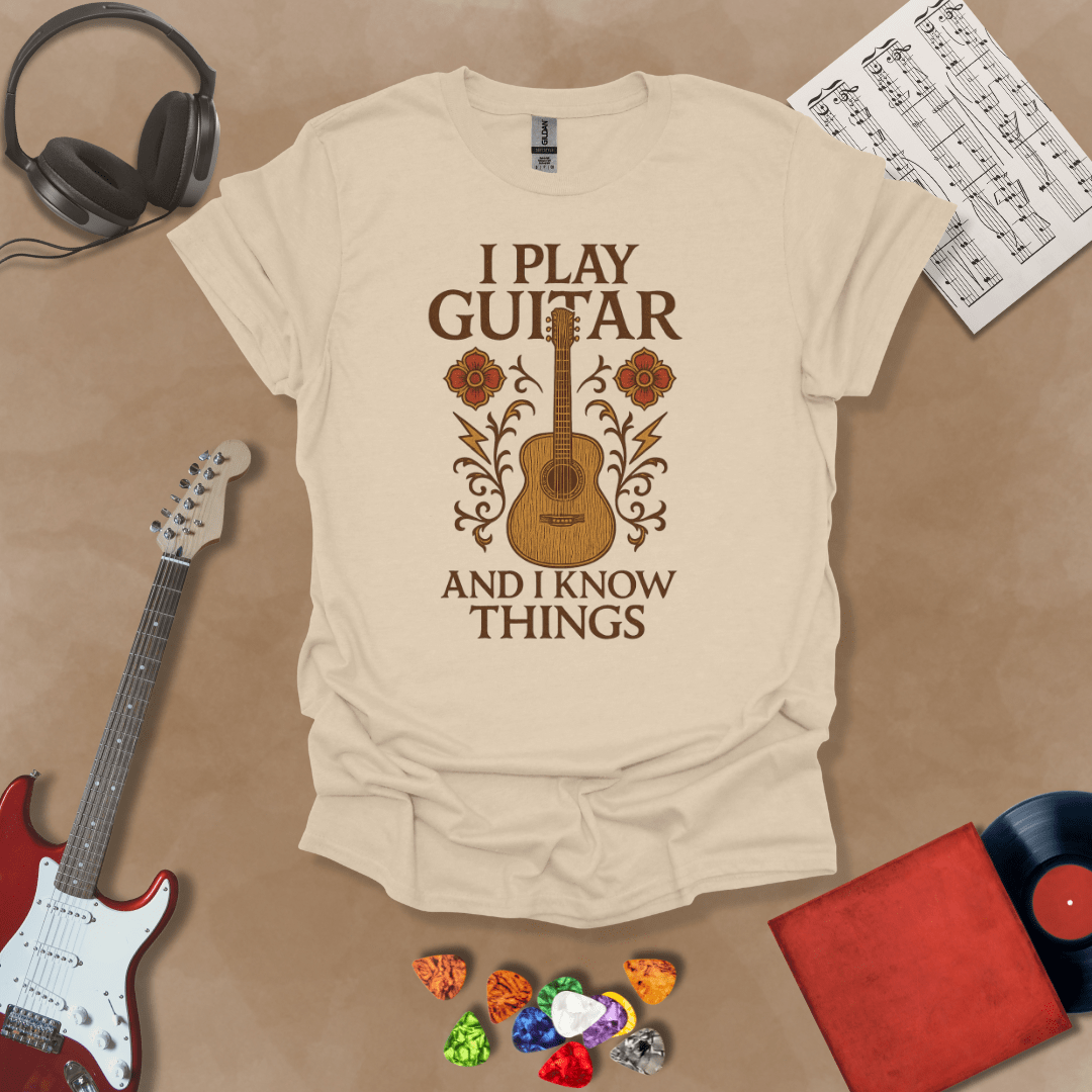 Beige t-shirt with bold medieval-inspired graphic and text “I Play Guitar and I Know Things,” blending rock style with witty humor by Riff Junkie.
