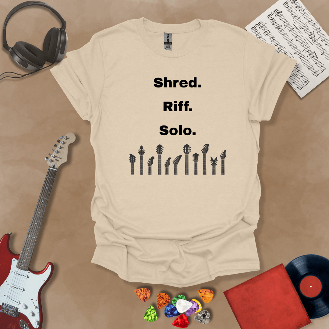 Beige T-shirt with text 'Shred. Riff. Solo.' with row of guitar headstocks silhouette