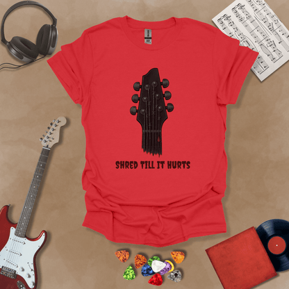 Red t-shirt with distressed guitar graphic, text “Shred ’Til It Hurts.”