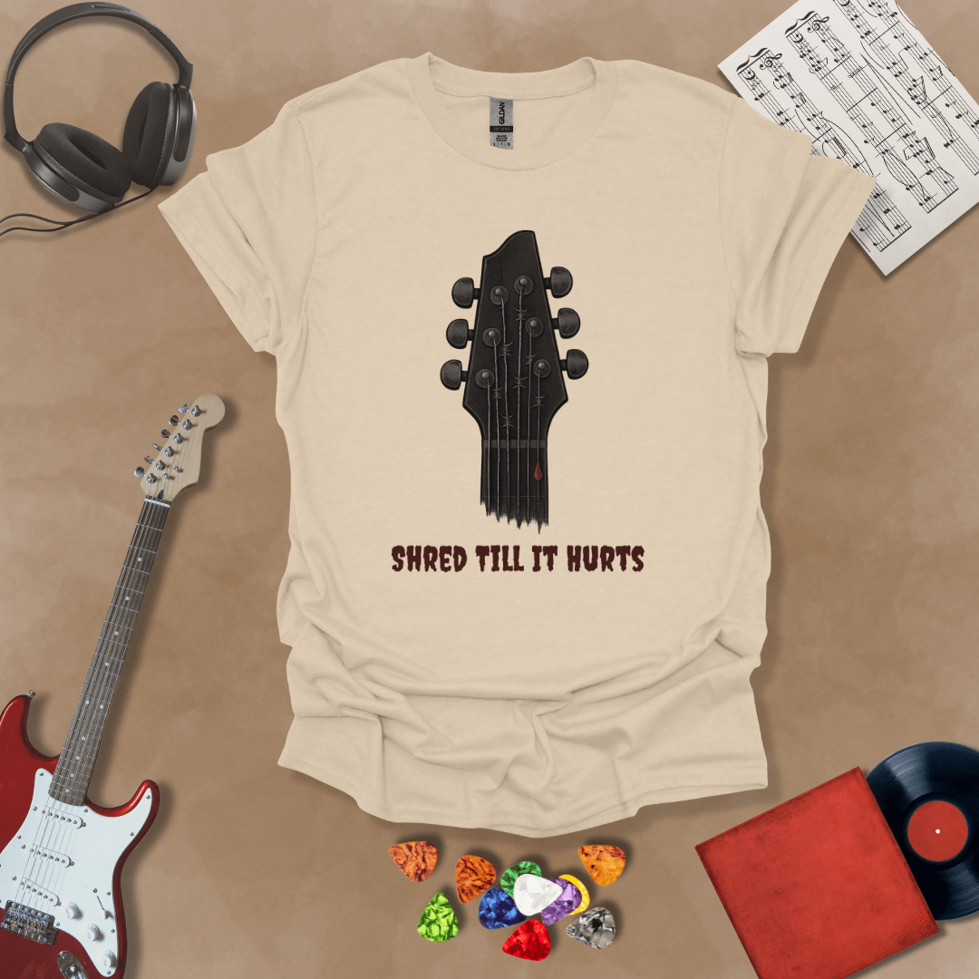 Beige t-shirt with distressed guitar graphic, text “Shred ’Til It Hurts.”