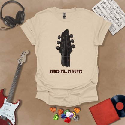 Beige t-shirt with distressed guitar graphic, text “Shred ’Til It Hurts.”