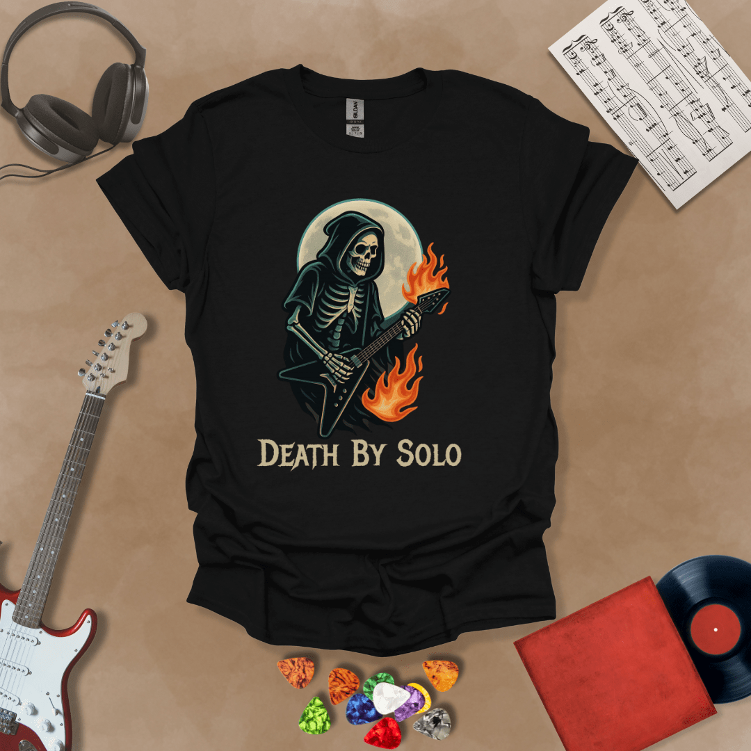 Black t-shirt with a graphic of a grim reaper skeleton playing a flaming V-style guitar under a glowing full moon, with the text “Death By Solo” below.
