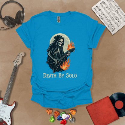 Blue t-shirt with a graphic of a grim reaper skeleton playing a flaming V-style guitar under a glowing full moon, with the text “Death By Solo” below.
