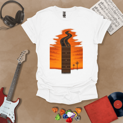 White t-shirt with long guitar neck blending into a road under sunset sky.
