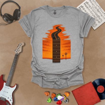 Gray t-shirt with long guitar neck blending into a road under sunset sky.
