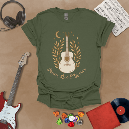 Green t-shirt featuring an acoustic guitar surrounded by leaves, moons, and stars in an earthy, bohemian line-art style, with the text “Peace, Love & Guitar” below.
