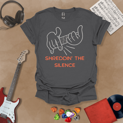 Gray t-shirt featuring cartoon-style hands shredding a guitar riff with the text “Shreddin’ the Silence” in bold orange letters.
