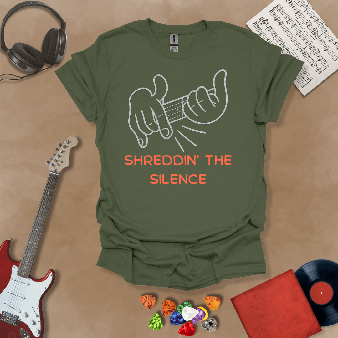 Green t-shirt featuring cartoon-style hands shredding a guitar riff with the text “Shreddin’ the Silence” in bold orange letters.
