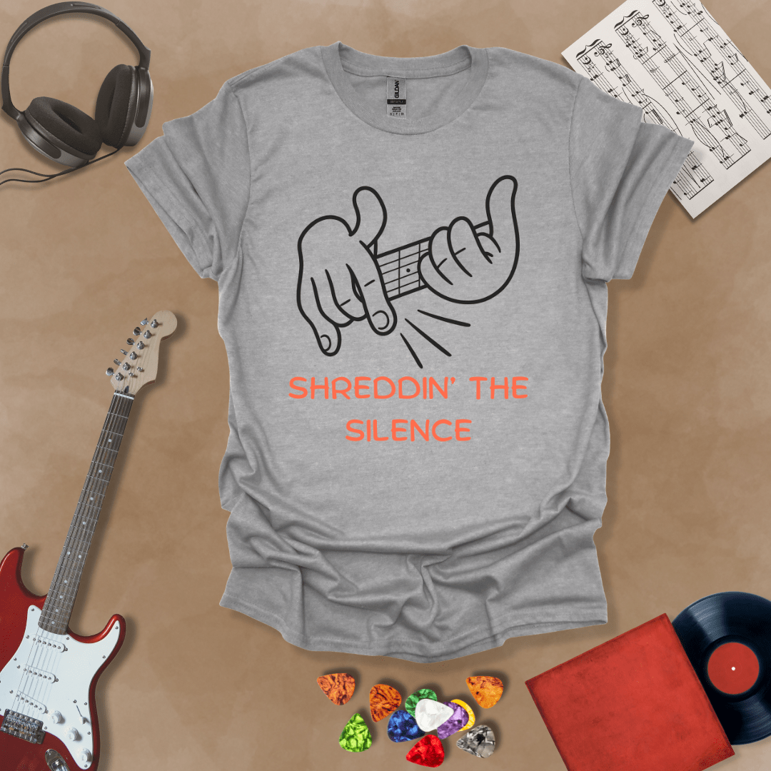 Gray t-shirt featuring cartoon-style hands shredding a guitar riff with the text “Shreddin’ the Silence” in bold orange letters.

