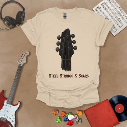 Beige t-shirt featuring a guitar headstock with razor-wire steel strings and a drop of blood, with the text “Steel Strings & Scars” below.
