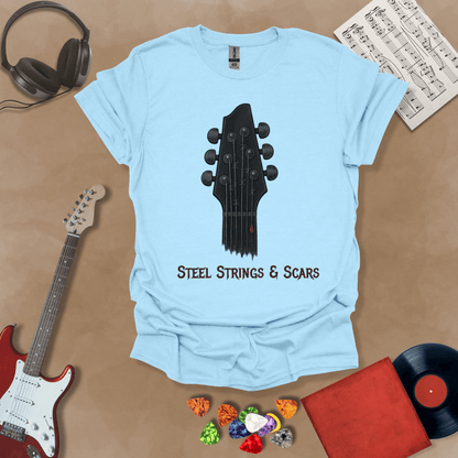 Light Blue t-shirt featuring a guitar headstock with razor-wire steel strings and a drop of blood, with the text “Steel Strings & Scars” below.
