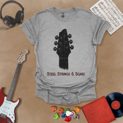 Gray t-shirt featuring a guitar headstock with razor-wire steel strings and a drop of blood, with the text “Steel Strings & Scars” below.
