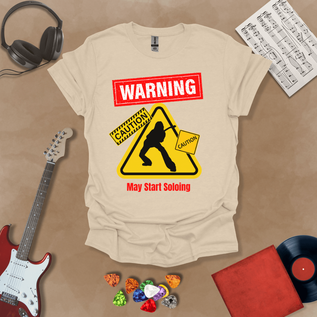 Beige t-shirt with bold red “Warning” text, yellow caution triangle with guitarist silhouette, text “May Start Soloing.”
