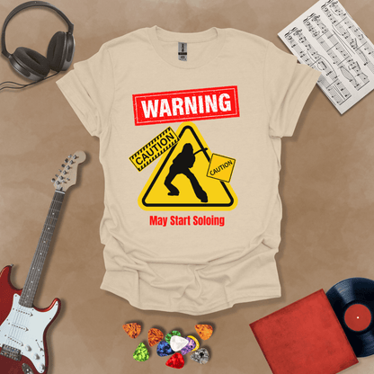 Beige t-shirt with bold red “Warning” text, yellow caution triangle with guitarist silhouette, text “May Start Soloing.”
