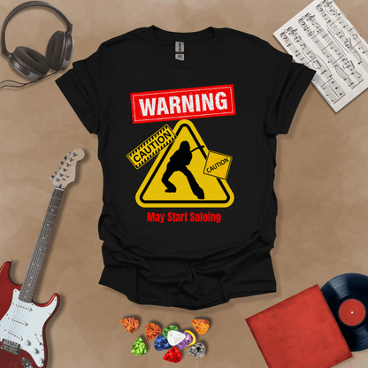 Black t-shirt with bold red “Warning” text, yellow caution triangle with guitarist silhouette, text “May Start Soloing.”
