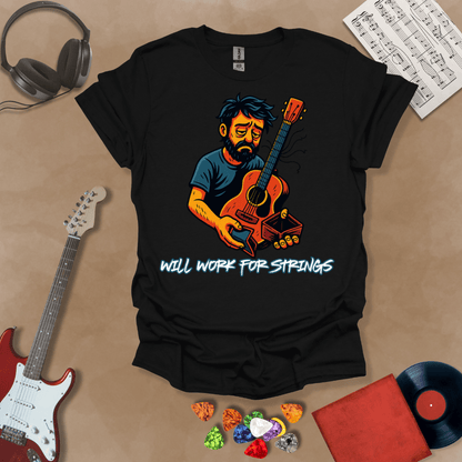 Black t-shirt with a graphic of Cartoon-style illustration of a scruffy man holding a broken guitar and an empty wallet, looking sad. and text 'Will work for strings' .