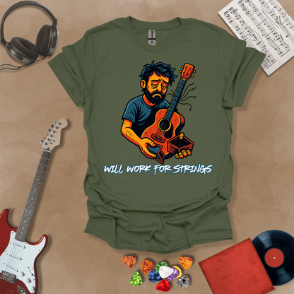 Green t-shirt with a graphic of Cartoon-style illustration of a scruffy man holding a broken guitar and an empty wallet, looking sad. and text 'Will work for strings' .