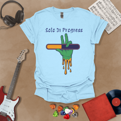 Light blue t-shirt with green zombie-like hand holding a colorful loading bar, text “Solo in Progress.”