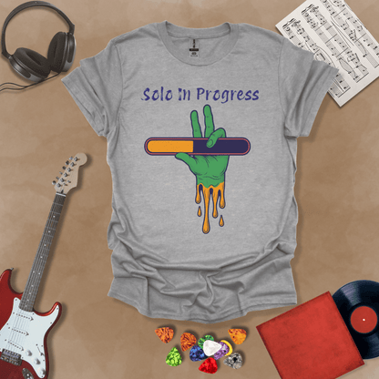 Gray t-shirt with green zombie-like hand holding a colorful loading bar, text “Solo in Progress.”