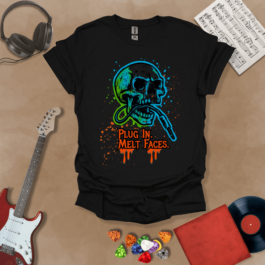 Black t-shirt with neon-colored skull biting a guitar cable, paint splatter effect, text “Plug In. Melt Faces.”