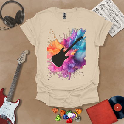 Beige t-shirt with Black electric guitar silhouette bursting through vibrant paint splash explosion in orange, pink, purple, and blue, abstract art tee design.
