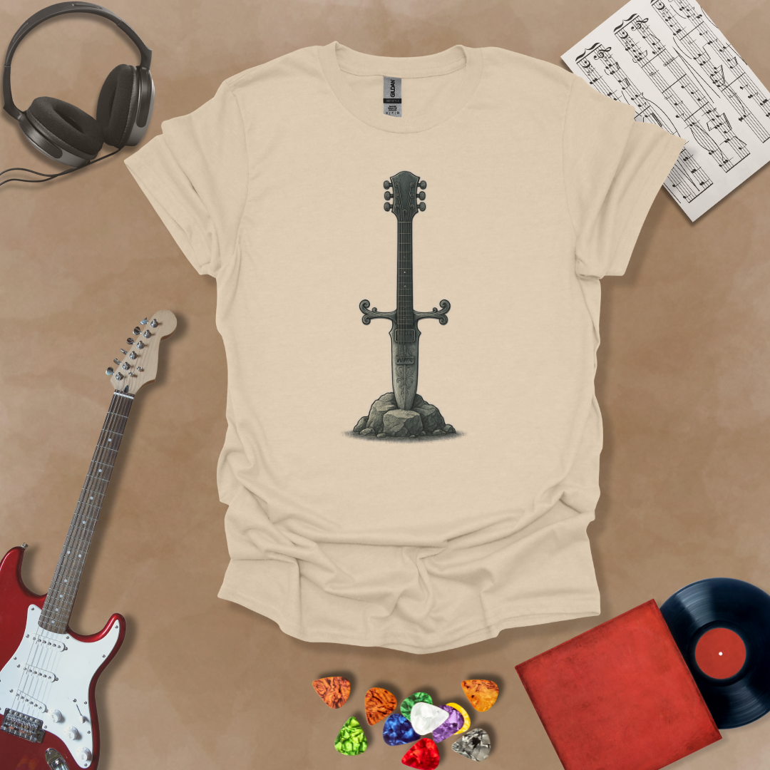Beige T-shirt with detailed illustration of a stone-forged guitar sword glowing in silver tones, titled Axecalibur: Blade of Light, printed on a light tee by Riff Junkie.