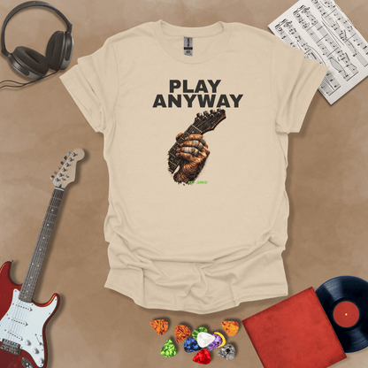 Play Anyway – Riff Edition graphic Beige t-shirt featuring bold stacked text above a weathered hand gripping a guitar fretboard with taped fingers and Riff Junkie branding.