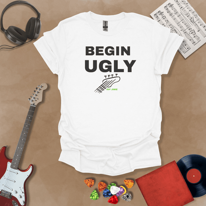 Begin Ugly – Jax Edition white graphic t-shirt featuring bold stacked text with distressed guitar headstock accent and subtle Riff Junkie branding. Motivational creator apparel design.