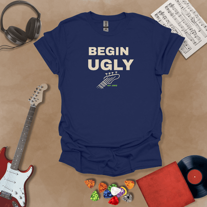 Begin Ugly – Jax Edition navy graphic t-shirt featuring bold stacked text with distressed guitar headstock accent and subtle Riff Junkie branding. Motivational creator apparel design.