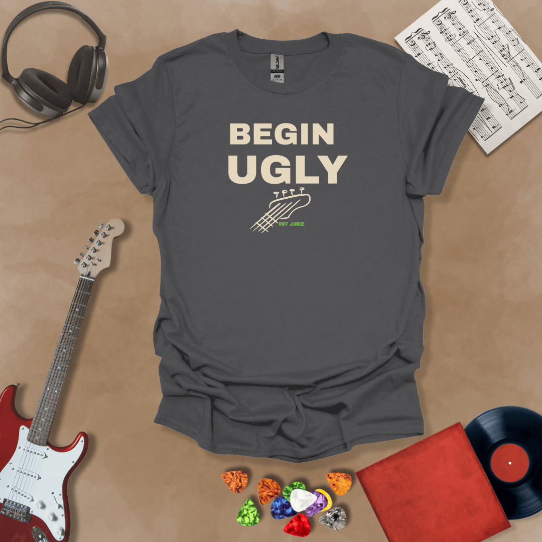 Begin Ugly – Jax Edition gray graphic t-shirt featuring bold stacked text with distressed guitar headstock accent and subtle Riff Junkie branding. Motivational creator apparel design.