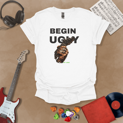 Begin Ugly – Riff Edition white graphic t-shirt featuring bold stacked text above a weathered hand gripping a guitar fretboard with taped fingers and subtle Riff Junkie branding.
