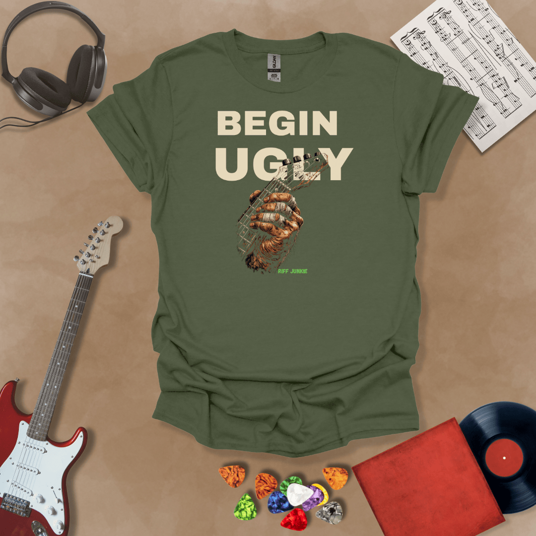 Begin Ugly – Riff Edition green graphic t-shirt featuring bold stacked text above a weathered hand gripping a guitar fretboard with taped fingers and subtle Riff Junkie branding.