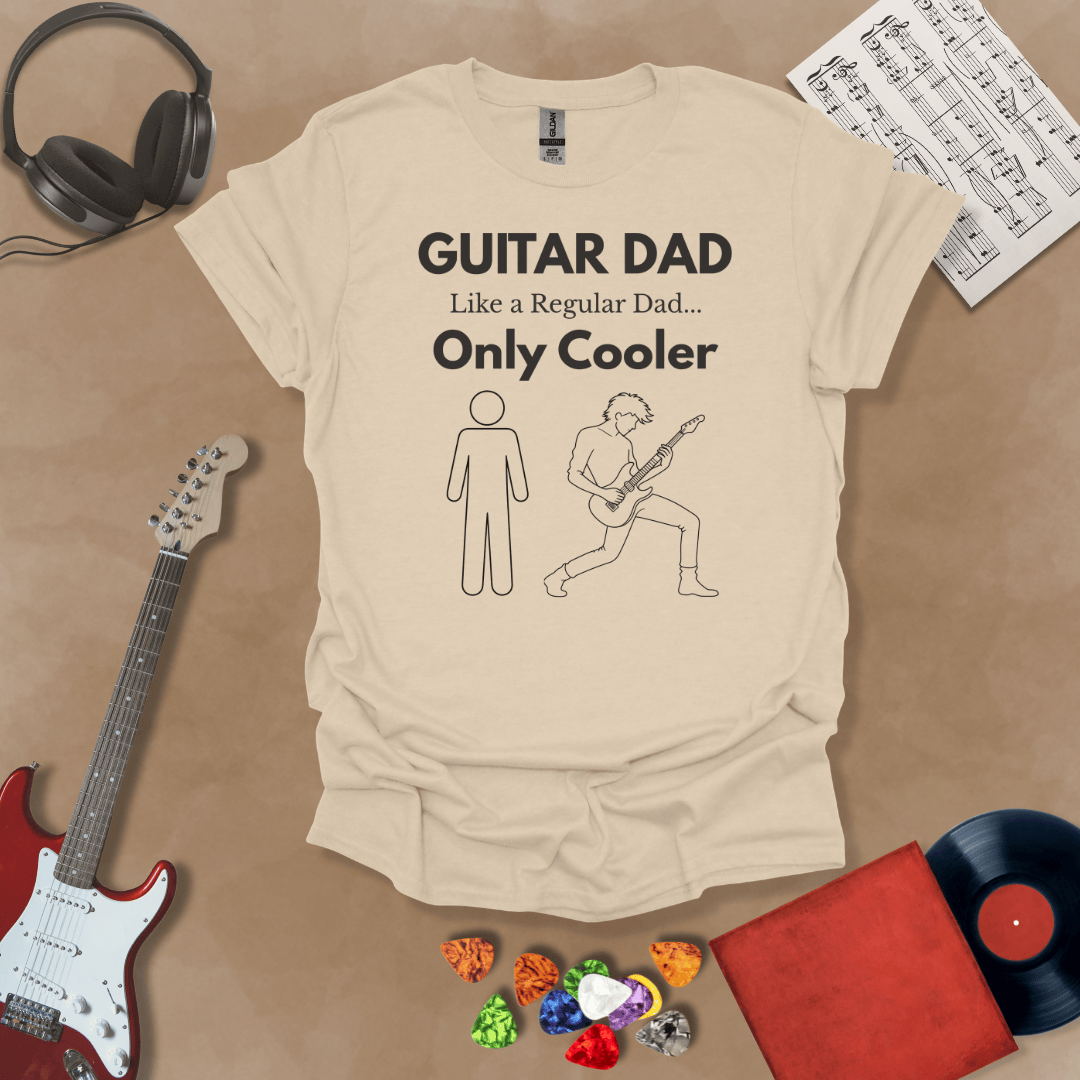 A beige Guitar Dad Sketch Edition t-shirt featuring a hand-drawn illustration of a regular dad and a rocker dad, laid flat on a tan background with guitar-themed props.