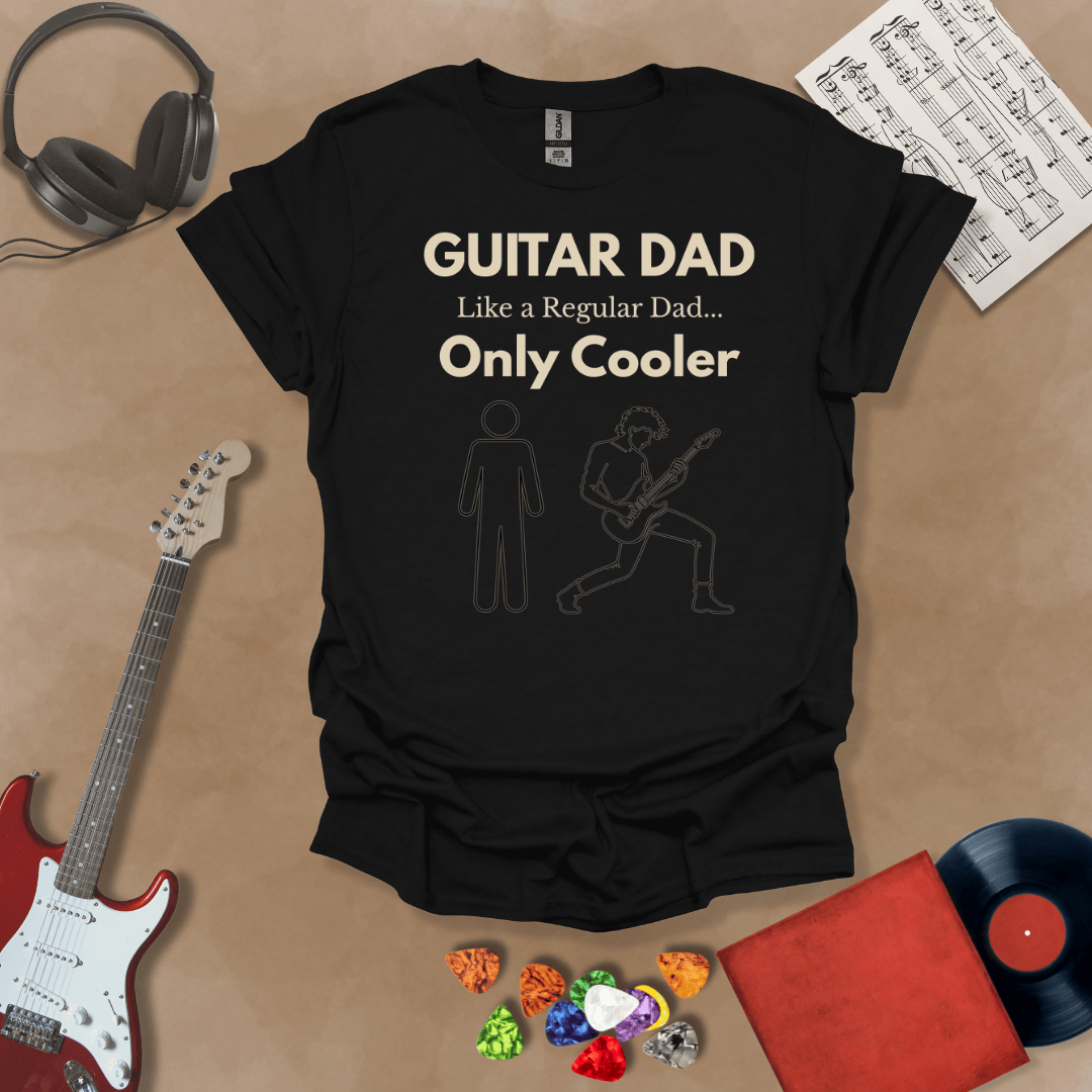 A black Guitar Dad Sketch Edition t-shirt featuring a hand-drawn illustration of a regular dad and a rocker dad, laid flat on a tan background with guitar-themed props.
