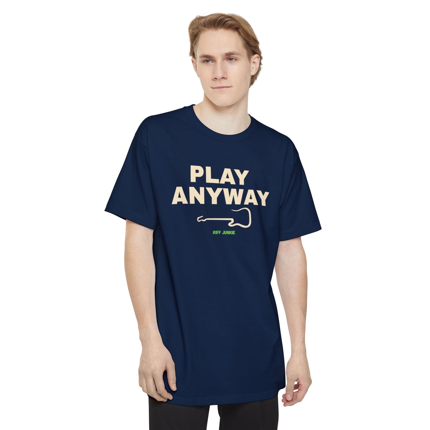 A man wearing a navy short-sleeve t-shirt with a graphic on the chest that reads 'PLAY ANYWAY' in beige block letters above a beige guitar outline and small green 'Riff Junkie' text, shown on a plain white background.
